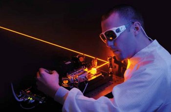 Foto von einem Mann, der eine schützende Brille trägt und gerade einen Laser justiert