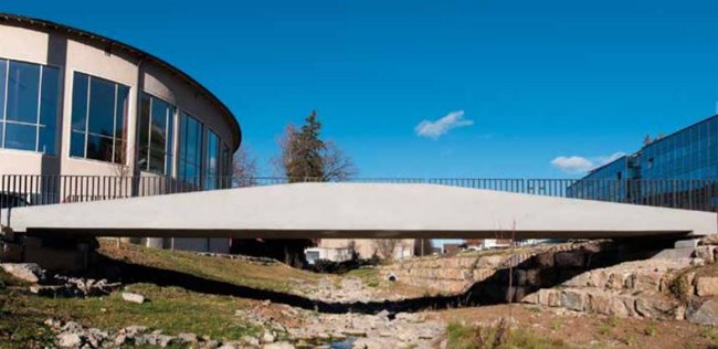 Seitenansicht der weißen Brücke, daneben ein Haus und im Hintergrund blauer Himmel