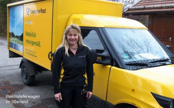 Foto des gelben Elektrolieferwagens der Deutschen Post; vor dem Lieferwagen steht Maria Hirschbichler