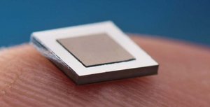 Ein quadratischer Chip, der von einem menschlichen Finger gehalten wird und nur einen Bruchteil des Fingers bedeckt
