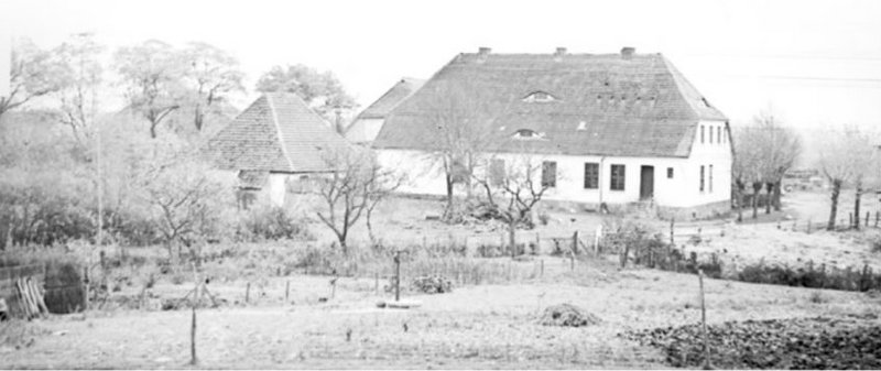 Schwarz-weiß Aufnahme des großen Gutshauses mit Landschaft im Vordergrund
