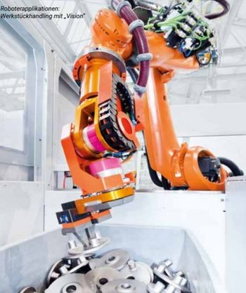 Große orangene Roboterhand in Bewegung, greift eine silberne Metallscheibe aus einer Kiste